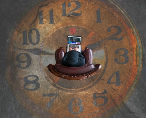 Man in het midden van een klok op zijn laptop